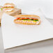 A sandwich wrapped in Choice newsprint sandwich wrap paper on a cutting board.
