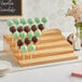 An Acopa natural wood skewer holder with chocolate cake pops on a table.