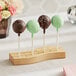 A wooden Acopa Mesa cake pop holder with three cake pops on sticks.