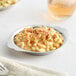 A stainless steel round au gratin dish filled with macaroni and cheese.
