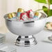 A silver bowl filled with cans of ice in a Choice stainless steel punch bowl.
