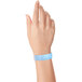A close-up of a hand with a light blue Carnival King wristband.