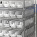 A metal shelf with white plastic Regency shelf bins.