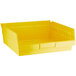 A close up of a yellow Regency plastic shelf bin.