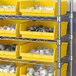 A shelf with Regency yellow plastic shelf bins holding white objects.