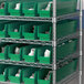 Metal shelving with Regency green bins holding white containers.