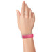 A close-up of a hand holding a pink Carnival King wristband.