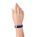 A close-up of a person's hand with a navy blue Carnival King wristband.