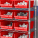 A metal shelving unit with red Regency shelf bins filled with white objects.