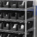 A metal shelving unit with black Regency plastic bins.