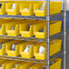 Regency yellow shelf bins on metal shelving with white objects inside.