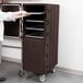 A woman using a Cambro double compartment tray and sheet pan carrier in a school kitchen.