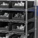 A metal shelving unit with black Regency shelf bins.