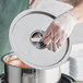 A person wearing gloves putting a Choice stainless steel lid on a pot of soup.