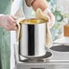 A person holding a Choice stainless steel bain marie pot with a towel over it.