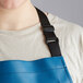 A woman wearing a blue Choice vinyl dishwasher apron with black straps.