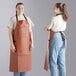 Two women wearing light brown and blue vinyl aprons.