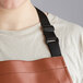 A woman wearing a Choice light brown vinyl apron with a black strap.