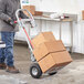 A man using a Lavex convertible hand truck to move stacked cardboard boxes.