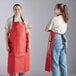 Two women wearing red Choice vinyl aprons over jeans.