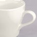 A close-up of a Tuxton Europa white cappuccino mug with a handle.