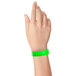 A close-up of a hand holding a neon green Carnival King wristband.