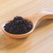 A wooden spoon filled with purple Organic Acai Powder.