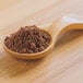 A wooden spoon full of brown Cacao Powder.