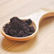 A wooden spoon with a pile of black Organic Maqui Powder.