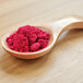 A spoon full of pink Cranberry Powder on a table.