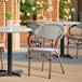 A Lancaster Table & Seating black and white outdoor arm chair on a patio with a table and chairs.