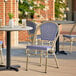 A Lancaster Table & Seating French Bistro blue and white outdoor side chair on a patio.