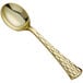 A Visions gold plastic soup spoon with a honeycomb design on the handle.