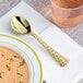 A Visions gold plastic soup spoon in a bowl of soup.