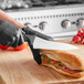 A person using a Schraf serrated bread knife to cut a sandwich.