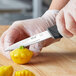 A person in gloves using a Schraf serrated paring knife to cut a yellow pepper.