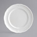 A close-up of an Acopa Condesa pearl white plate with a decorative scalloped edge.