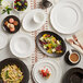 An Acopa Condesa pearl white porcelain saucer on a table with a white plate of food.