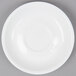 An Arcoroc white porcelain saucer with a circular design on a gray surface.