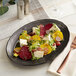 A plate of beet salad with goat cheese and vegetables on an Acopa Condesa scalloped porcelain platter.