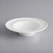 An Acopa Condesa white porcelain bowl with a scalloped rim on a gray background.