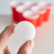 A person holding a Franmara white beer pong ball.