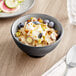An Acopa matte grey and black melamine bowl filled with oatmeal topped with fruit and nuts on a table.