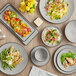 Acopa Apollo matte grey and black melamine plates of food on a table.
