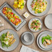 Acopa Apollo matte grey and black melamine plates on a table with food.