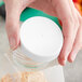 A hand holding a plastic container with a white 63/400 ribbed plastic cap on it.