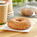 A Katz Gluten-Free cinnamon sugar donut on a napkin next to a cup of coffee.