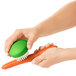 An OXO Good Grips green vegetable brush cleaning a carrot.