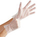 A person's hands wearing clear plastic Noble NexGen disposable gloves.