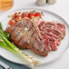 A plate with a Rastelli's USDA Prime Bone-In Porterhouse Steak, asparagus, and tomatoes.